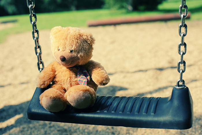 Bear doll sitting on the swing in the park